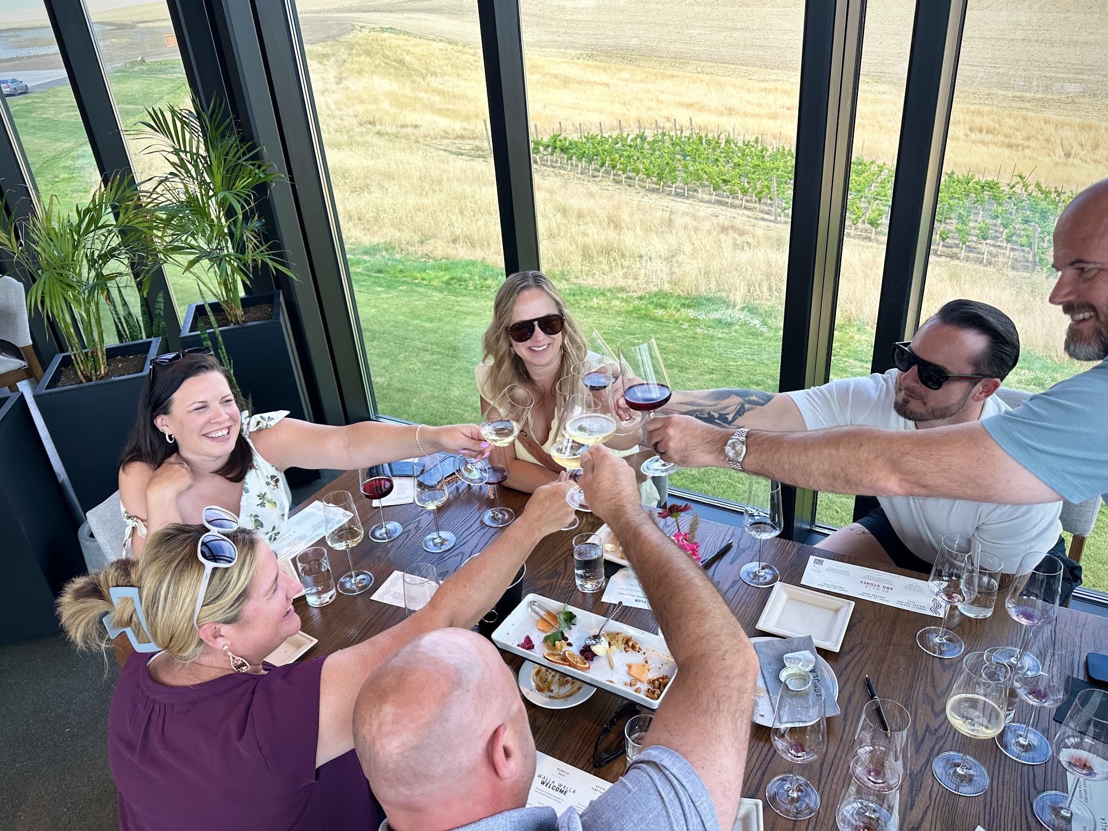 Guests toasting at a tasting room table overlooking the vineyard